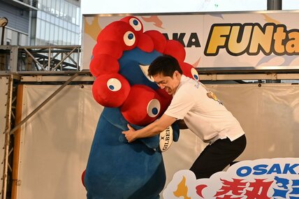 トライしようとするミャクミャクをディフェンスする吉村洋文知事